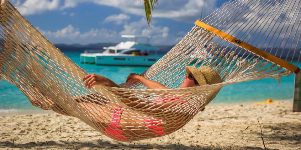 Woman relaxing in hammock with power catamaran in the background Woman relaxing in hammock with power catamaran in the background